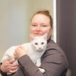 Amanda smiling inside holding a white cat