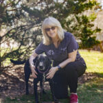 Tammy outside with a black lab