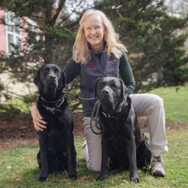 smiling female veterinarian with two black dogs
