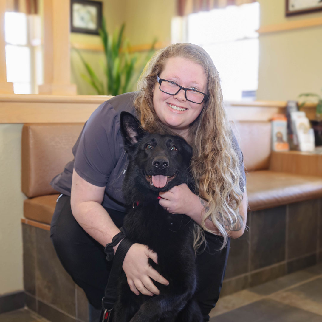 smiling female veterinary technician with a black dog