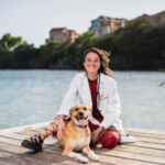 female veterinarian sitting on dock with large dog